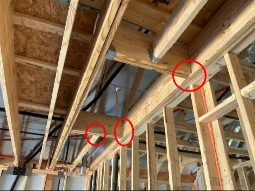 Floor joists without hangers, marked in red, found during a framing inspection